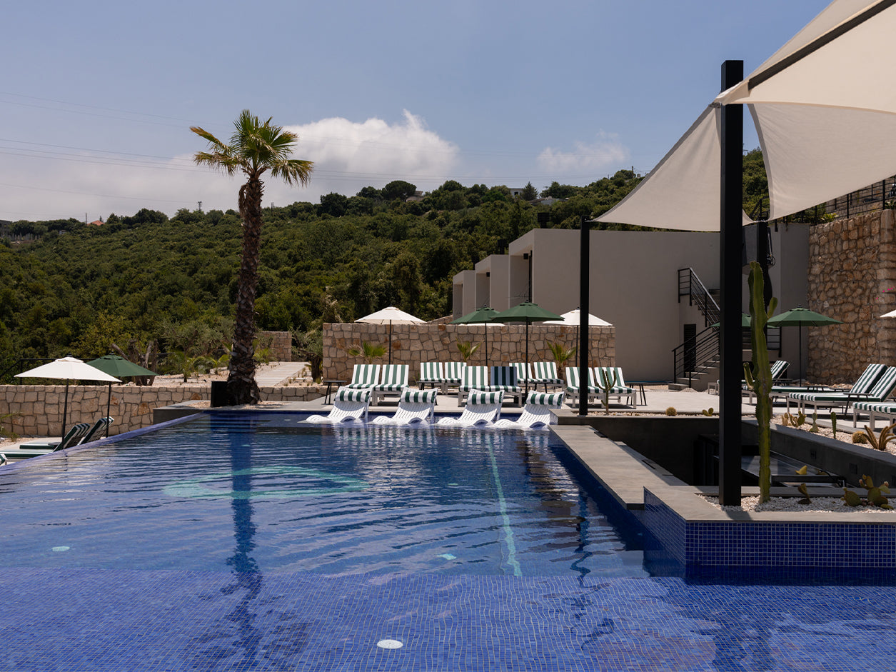 Maison Grès pool, palm trees, lounge chairs, and tropical landscaping